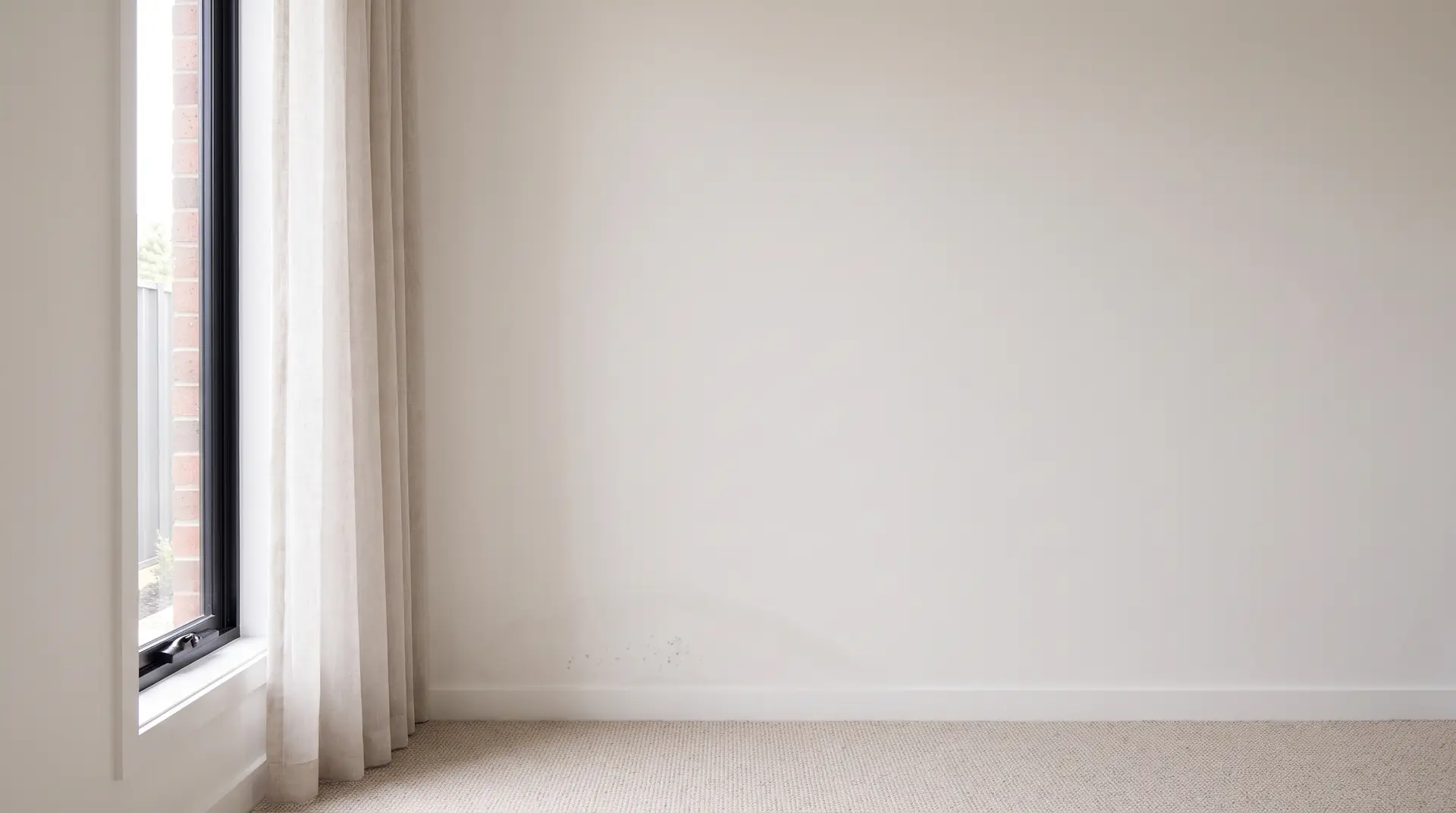 Illustration: a faint damp patch and a few mould spots above a skirting board, what a mould inspection looks for