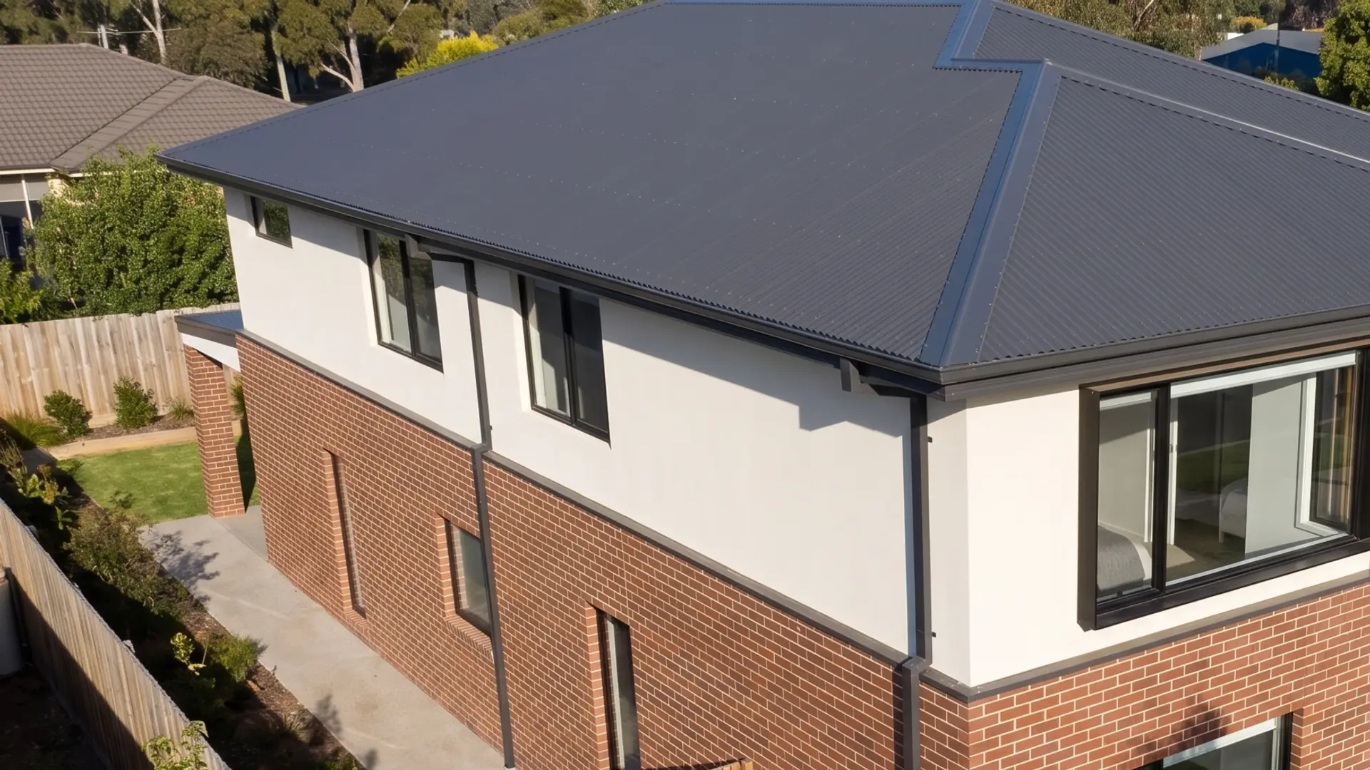 Illustration: the dark metal hip roof, eaves, gutters and downpipes of the two-storey home, seen from above