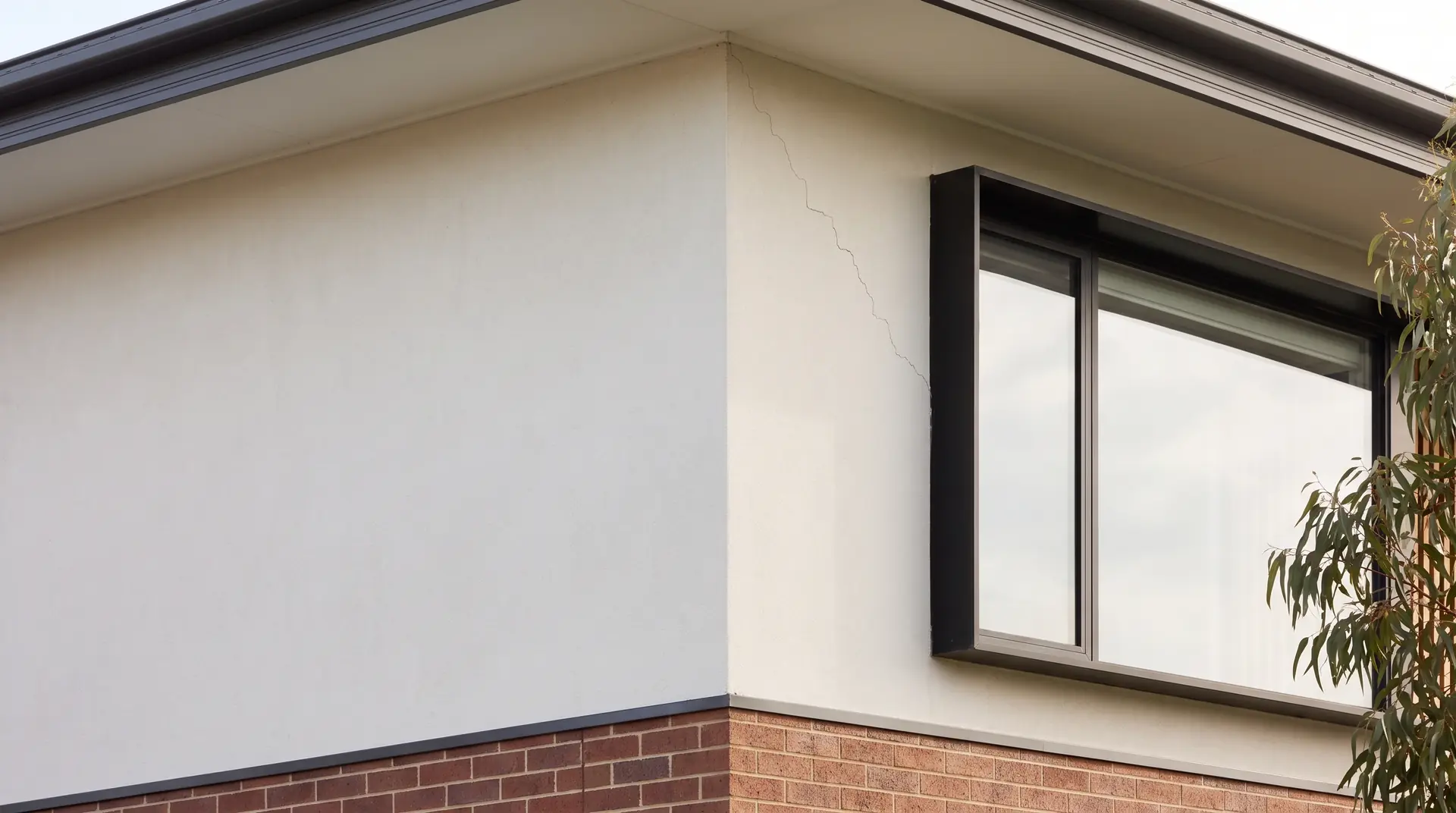 Illustration: a fine crack in the render at a window corner, the kind of mark a structural inspection looks at